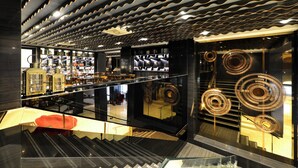 Een modern interieur met een trap, glazen balustrades en een gestreept plafond.