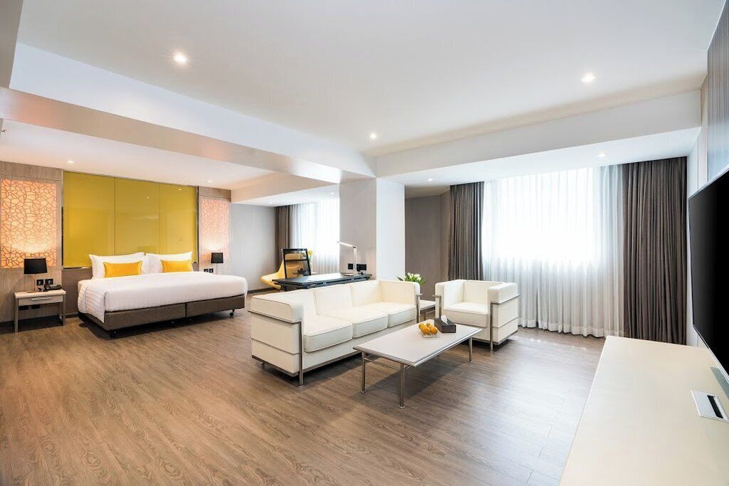 Une chambre d’hôtel moderne avec un grand lit, un canapé, une table basse et un téléviseur.