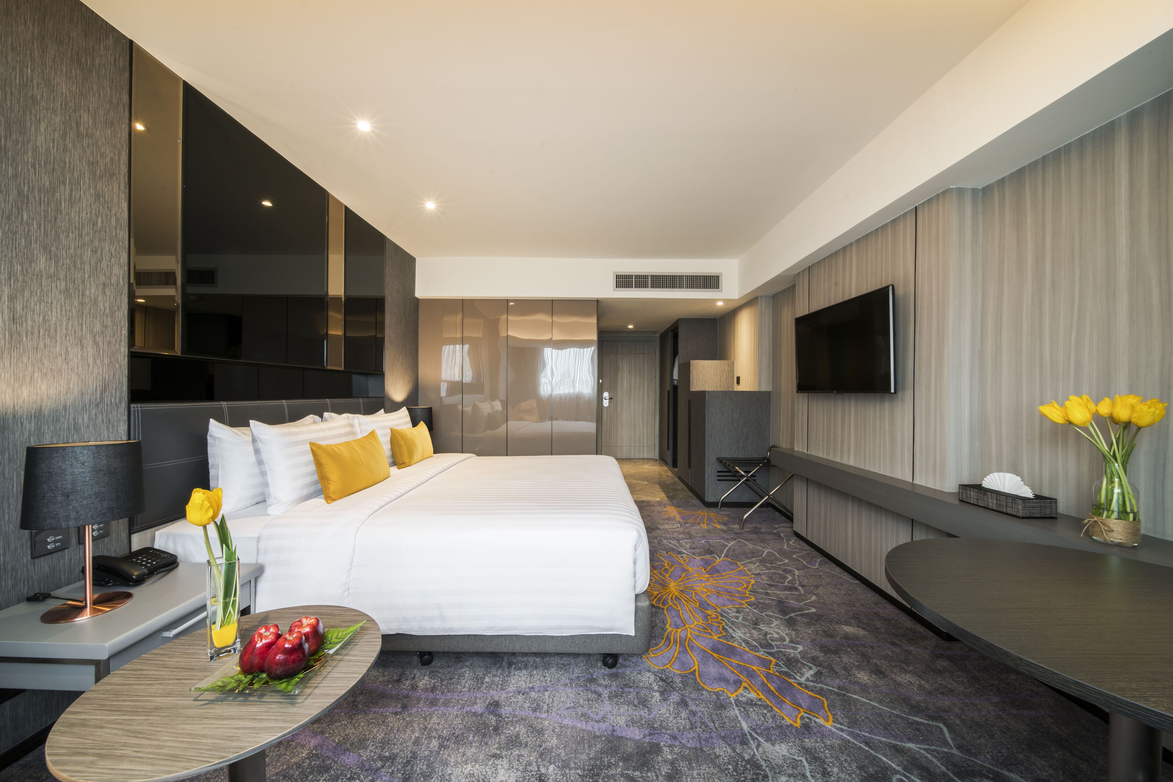 Ein modernes Hotelzimmer mit einem großen Bett, einem Nachttisch und einem Flachbildfernseher.
