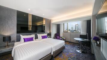 A hotel room with a large bed, a desk, a chair, and a view of the city.
