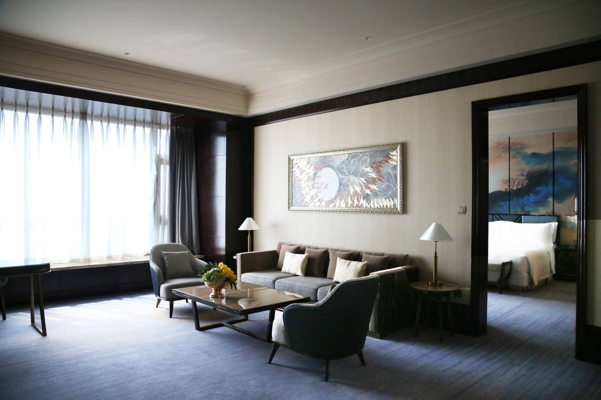 Une chambre d’hôtel avec un canapé, des fauteuils, une table basse et un tableau au mur.