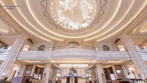 A grand lobby with a central chandelier, marble columns, and a high ceiling. - Chateau Star River Qing Dao (Qingdao)