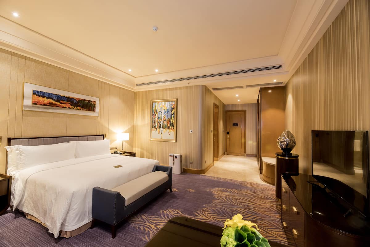 Une chambre d’hôtel avec un grand lit, un téléviseur à écran plat, un bureau et une chaise.