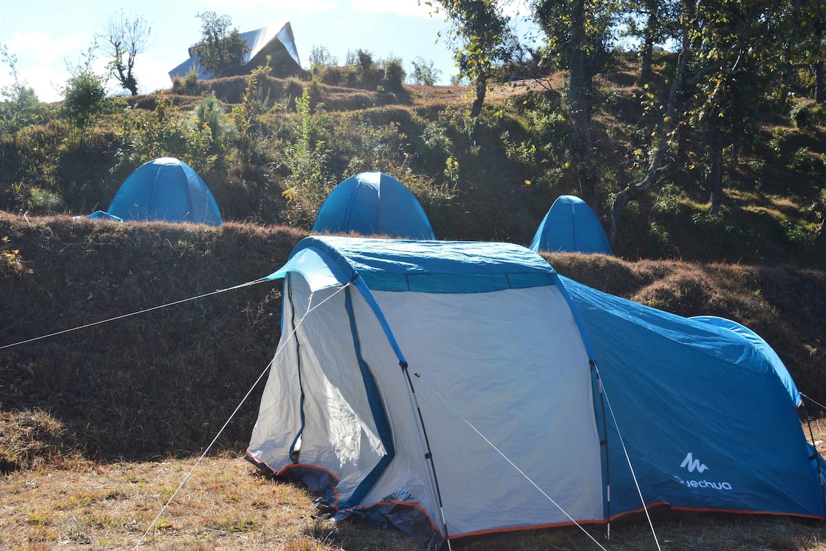 Um local de camping com tendas montadas numa colina gramada.