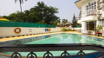 Relax by the pool surrounded by lush greenery and a clear blue water surface.