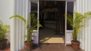 A entrada do Sunset Beach Resort, com uma placa, plantas em vasos e vista para o interior.
