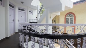 Interior claro com um guarda-corpo preto e branco ornamentado, uma escada e uma porta com janela.