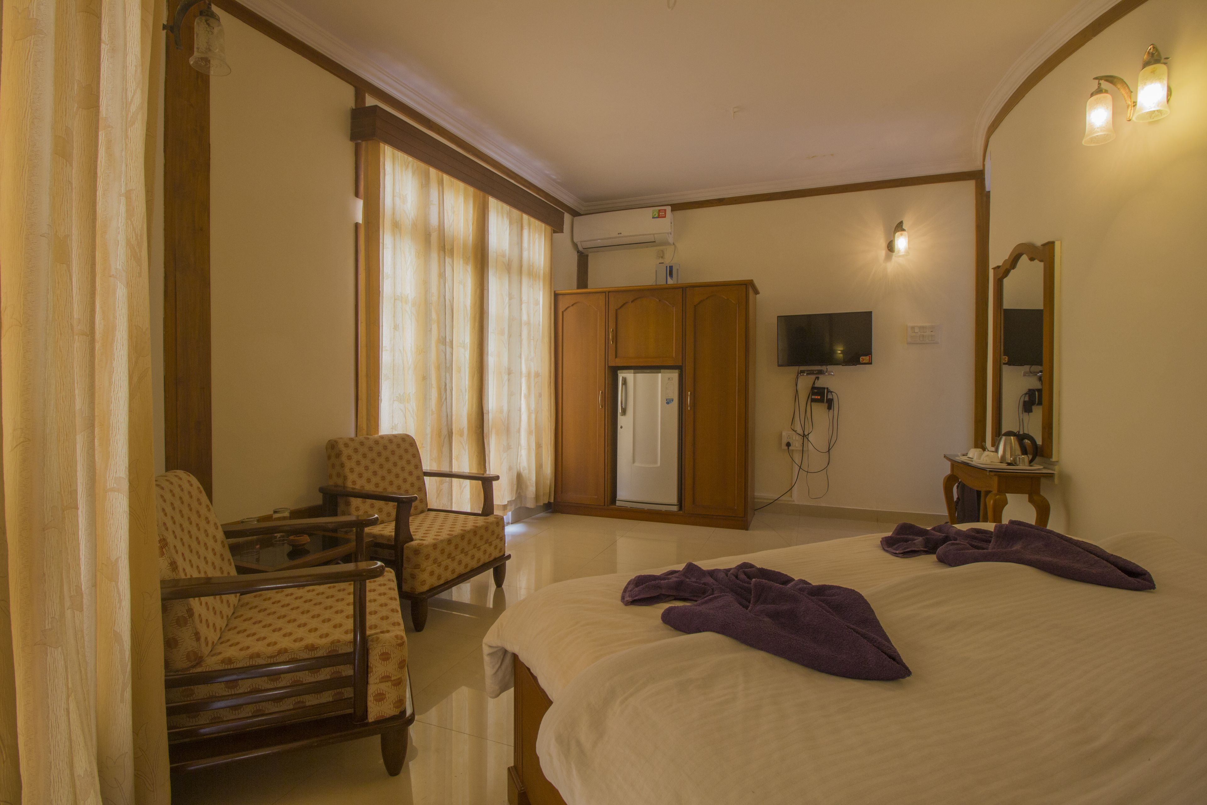 A hotel room with a bed, a chair, a desk, a television, and a mirror.