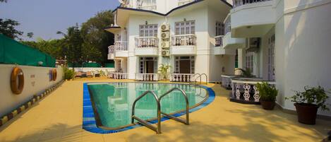 Un hotel con piscina, varios balcones y plantas en macetas.