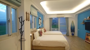 A room with two beds, a view of the sea through large windows, a surfboard on the wall, and a ceiling light. - After the Court Chiaohsi (Jiaoxi)