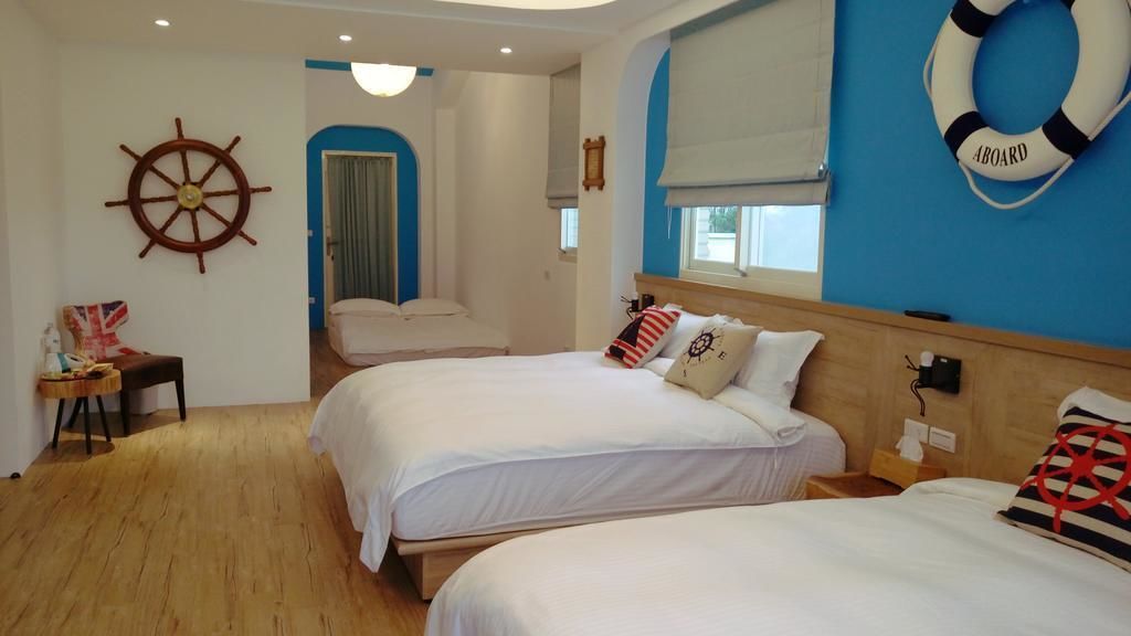 A room with two beds, a wooden floor, a ship's wheel, and a lifebuoy on the wall.