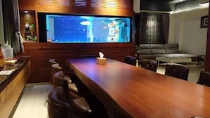A modern living room with a wooden dining table, bar stools, a flat-screen TV, and a sofa. - After the Court Chiaohsi (Jiaoxi)