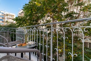 A balcony with a table and chairs, a pizza, and a glass of water. - Cutie by Stylish Stays (Athens)