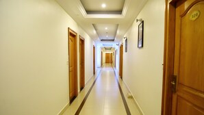 A hotel hallway with wooden doors, a tiled floor, and a ceiling with recessed lighting. - Asia Palace Hotel (Phnom Penh)