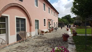 Een roze gebouw met een geplaveid binnenhof, terras en plantenpotten.