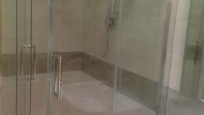 A glass-enclosed shower area with a handheld showerhead and a wall-mounted faucet. - B&B La Ferrovia (Benevento)