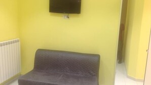 A room with a grey sofa, a television mounted on the wall, and a radiator. - B&B La Ferrovia (Benevento)