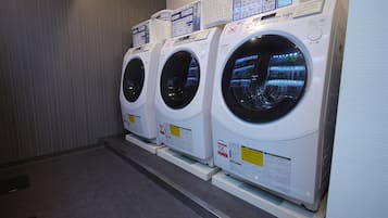 A row of three white front-loading washing machines in a commercial setting.