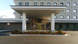 A modern hotel with a covered entrance, multiple floors, and a parking area.