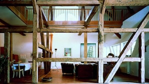 A spacious interior with exposed wooden beams, a dining area with a table and chairs, and a staircase leading to an upper level. - Seehotel am Neuklostersee (Zurow)