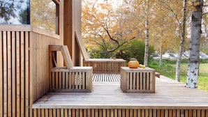 A wooden deck with built-in seating and a view of autumn trees. - Seehotel am Neuklostersee (Zurow)