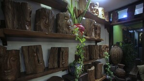 A room with wooden wall shelves displaying various wooden sculptures and planters. - Villa Elita (Sudipen)