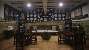 A cozy dining area with a central bench, surrounded by wooden chairs, and a wall adorned with numerous plates. - Villa Elita (Sudipen)