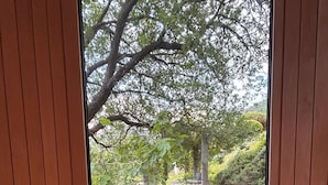 Quarto moderno com uma janela grande, grade preta e piso de madeira.