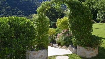 A garden with a stone pathway leading to a circular archway surrounded by lush greenery.