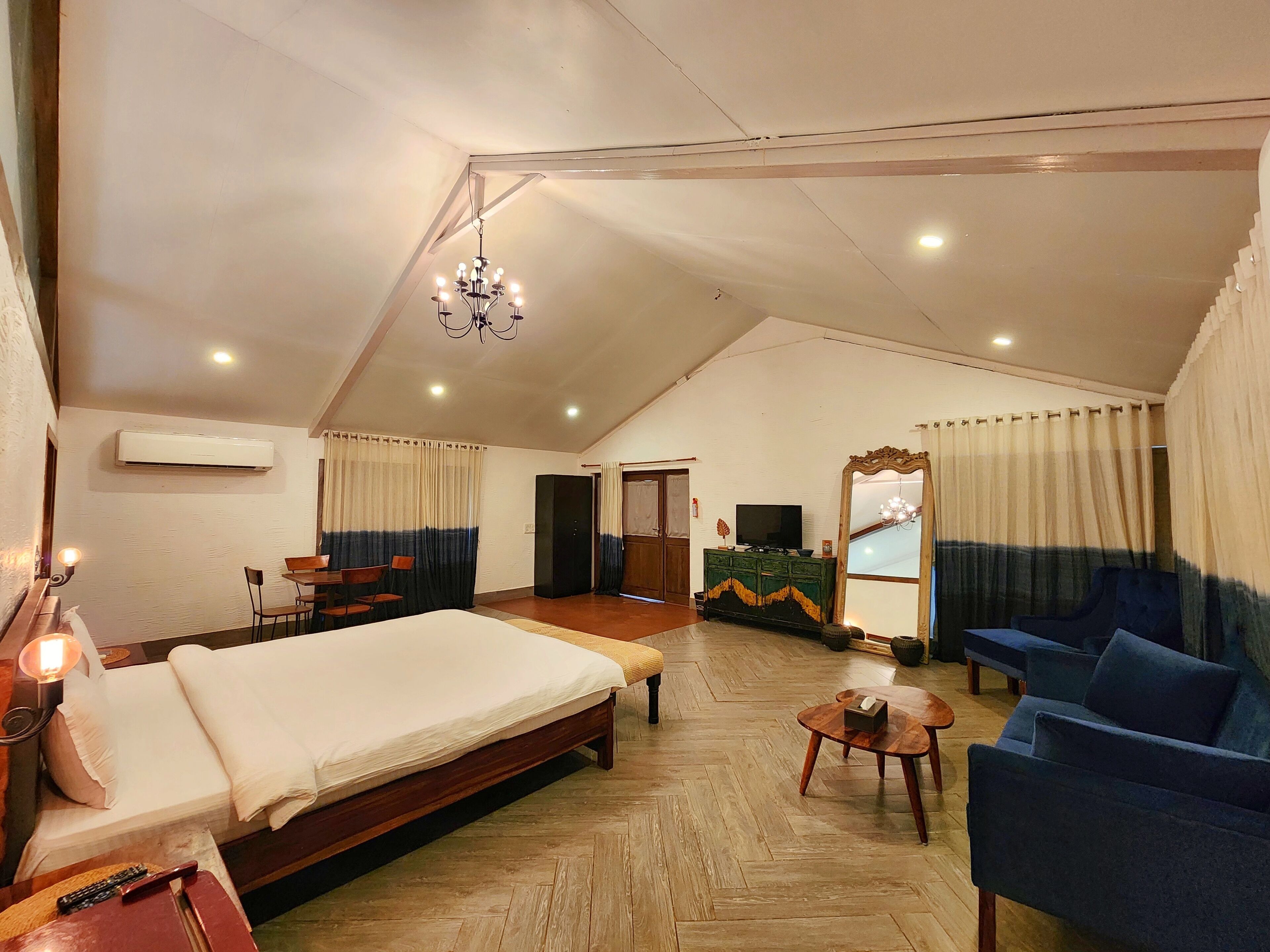 A spacious room with a large bed, a sofa, a small table, and a television.
