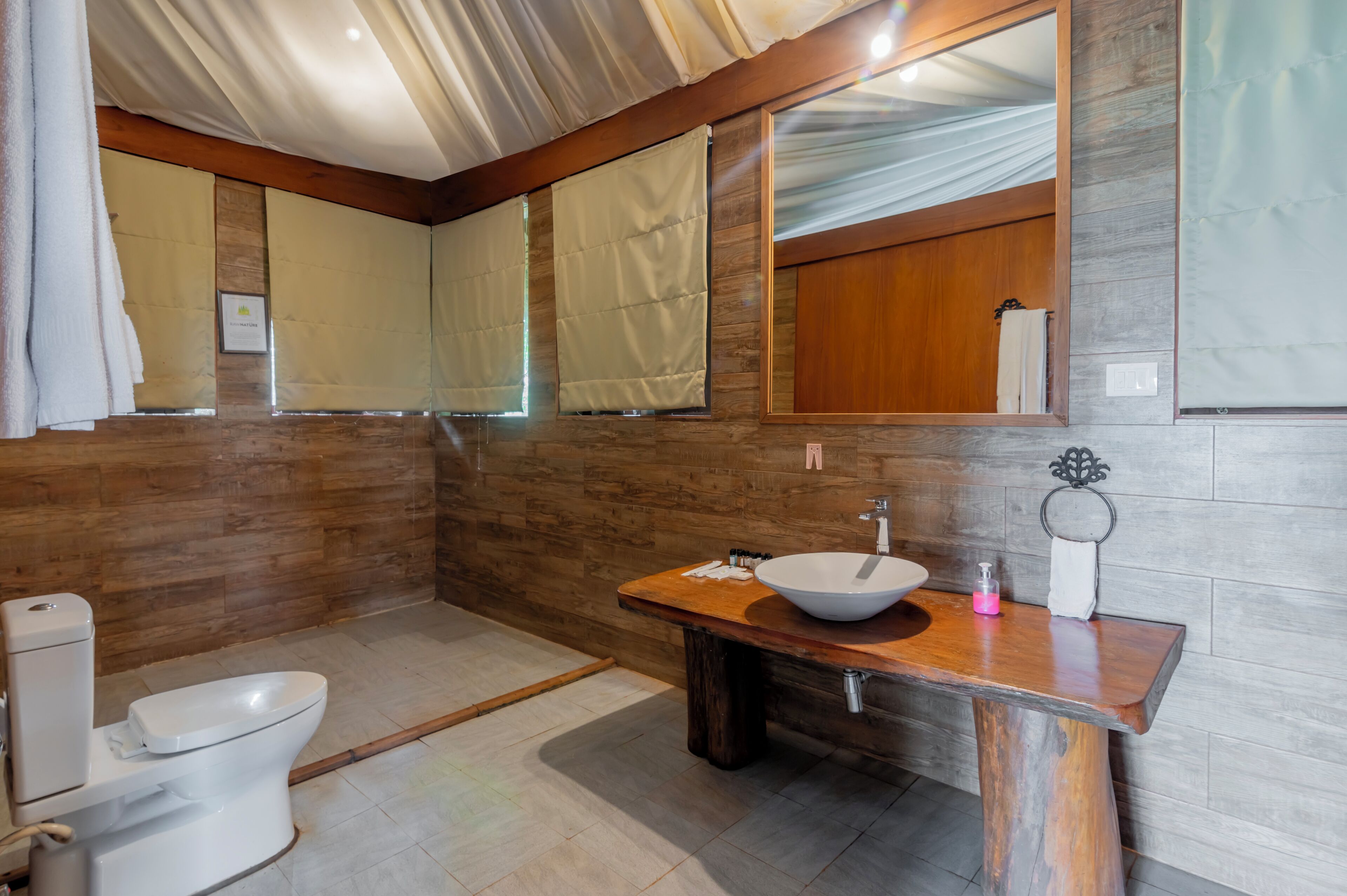 A bathroom with a wooden vanity, a white sink, and a toilet.