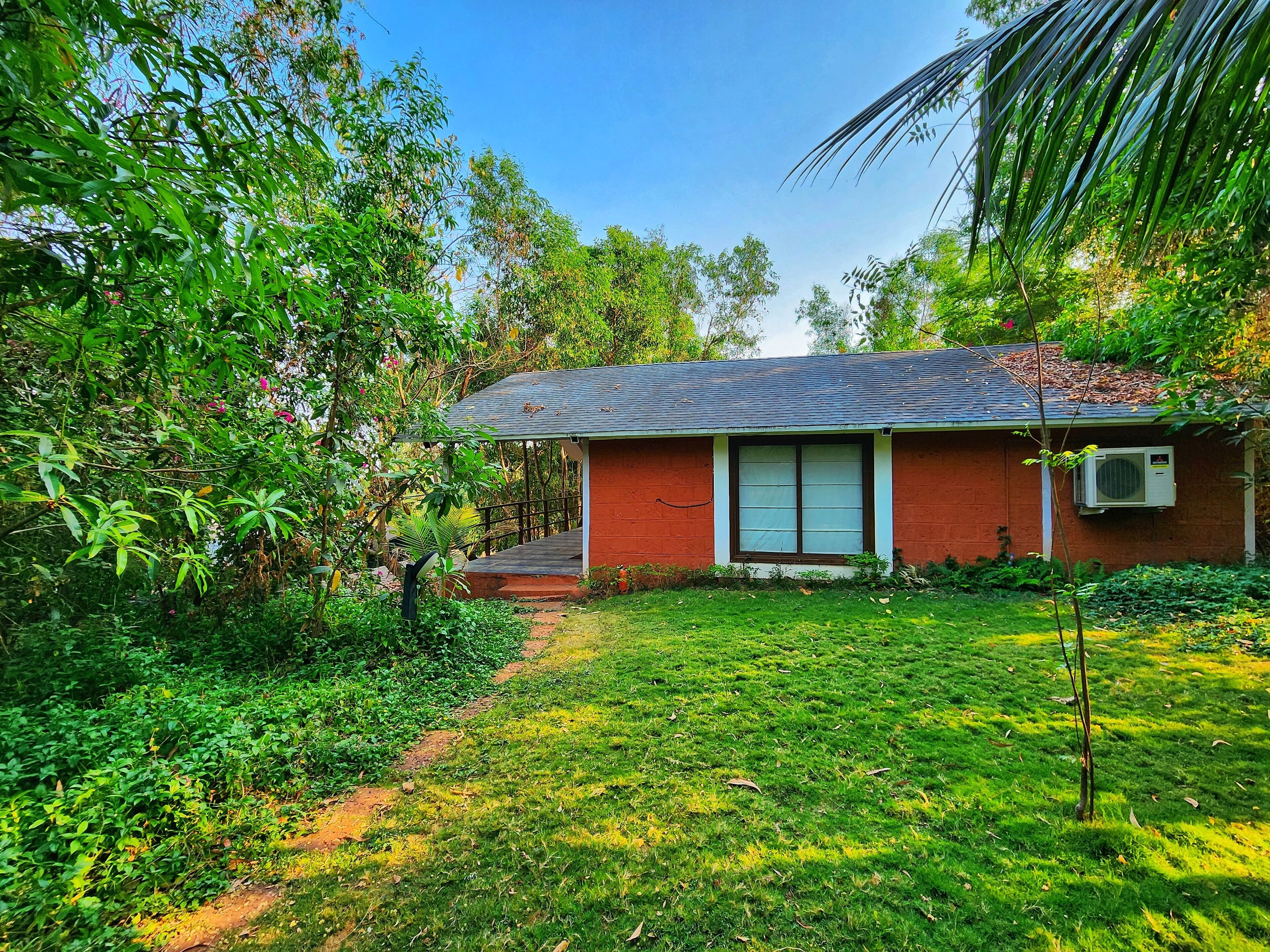 A single-story house with a red brick exterior, a dark shingled roof, and a small front porch.