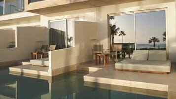 Un espace piscine moderne avec un canapé et des fauteuils, une table et une vue sur l’océan.
