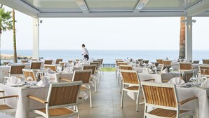 A restaurant with tables set for dining, overlooking the ocean. - Sunrise Jade - Adults Only (Paralimni)