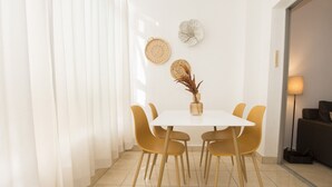 A dining area with a white table, four yellow chairs, a vase with dried plants, and decorative wall art. - A37 APOLO 4 ESC 4 4º 16 (Calpe)