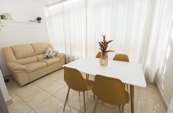 A living room with a beige sofa, a white table, and yellow chairs.