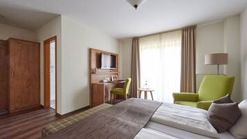 Una habitación de hotel con una cama, un escritorio con una silla, un televisor y una lámpara.