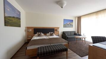 Een hotelkamer met een bed, een bureau, een stoel, een bank en twee schilderijen aan de muur.