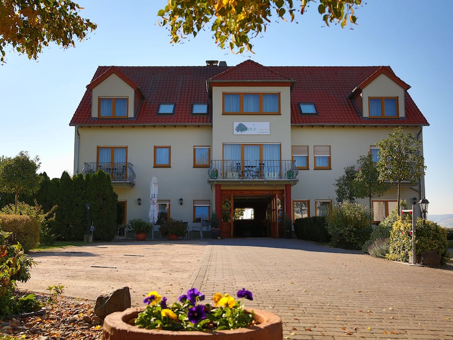 Ein zweistöckiges Gebäude mit rotem Ziegeldach, einem Balkon und einem Schild mit der Aufschrift 'Hotel's'.