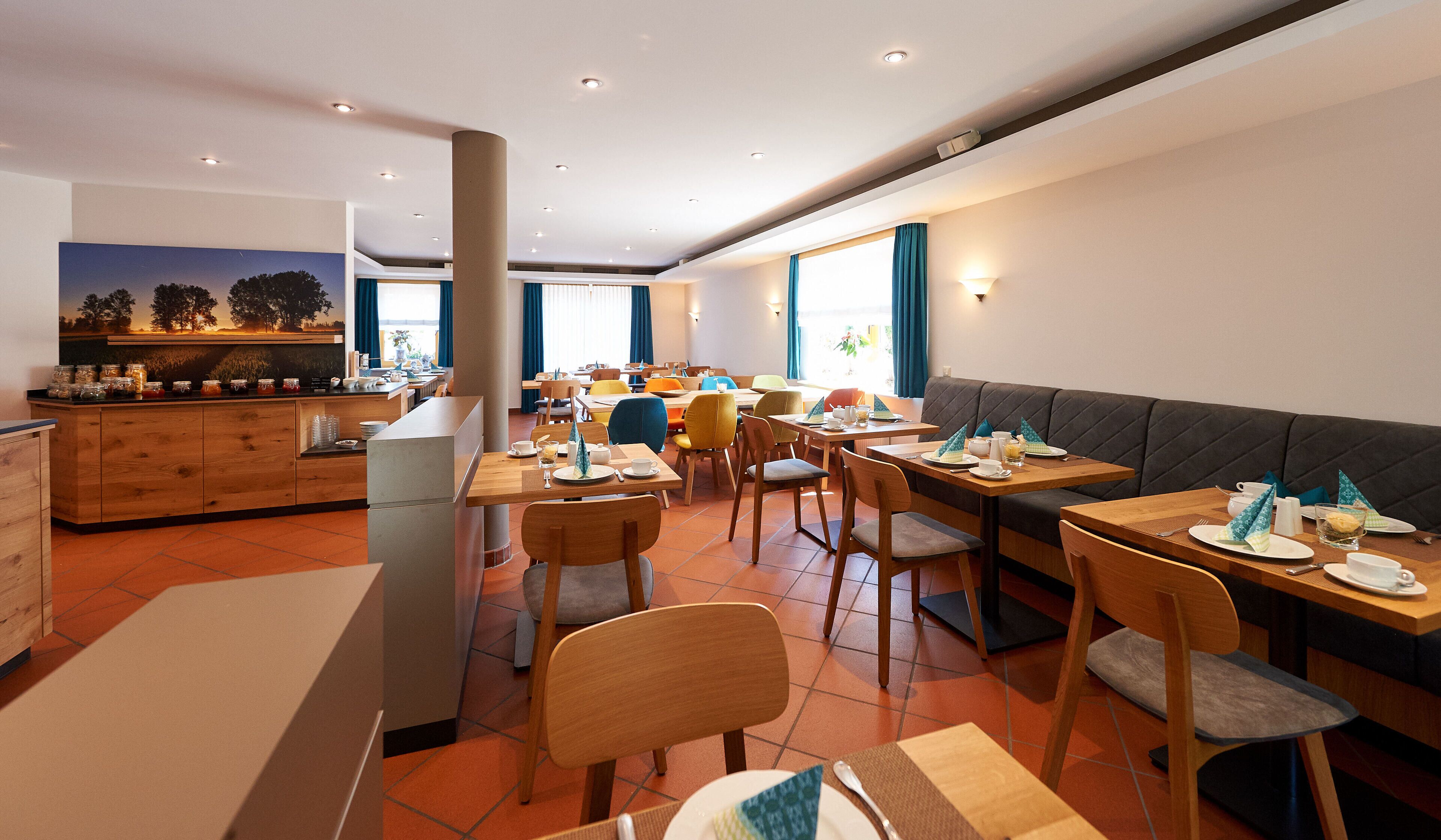A modern dining area with wooden tables and chairs, a bar area with a counter, and a large window with curtains.