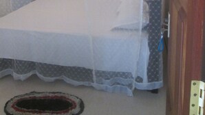 Una cama individual con dosel, una puerta con pomo azul y una cortina estampada.
