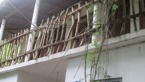 Un edificio con valla de bambú, una lámpara colgante y una ventana con reja de metal.