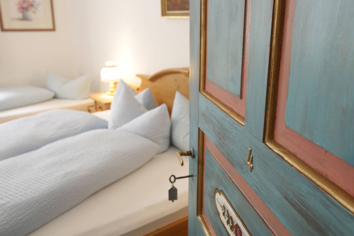 A bedroom with two beds, a nightstand, and a dresser with a key hanging on the door.