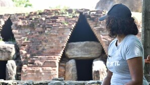 Una persona de pie frente a antiguas estructuras de ladrillo con grandes bloques de piedra.