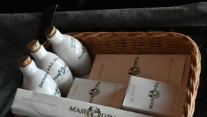 Una cesta de mimbre con botellas y cajas etiquetadas 'MAHORA'.