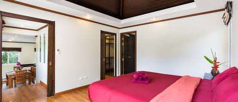 A bedroom with a large bed, wooden flooring, and a skylight.