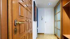 A wooden door with a brass handle and a keyhole, leading to a room with a white door and a blue wall. - A Diamont of 140 m2 Apt (Athens)
