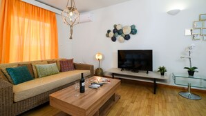 A living room with a sofa, coffee table, TV, and decorative wall art. - A Diamont of 140 m2 Apt (Athens)