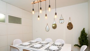 A dining area with a white table set for six, surrounded by white chairs. - A Diamont of 140 m2 Apt (Athens)