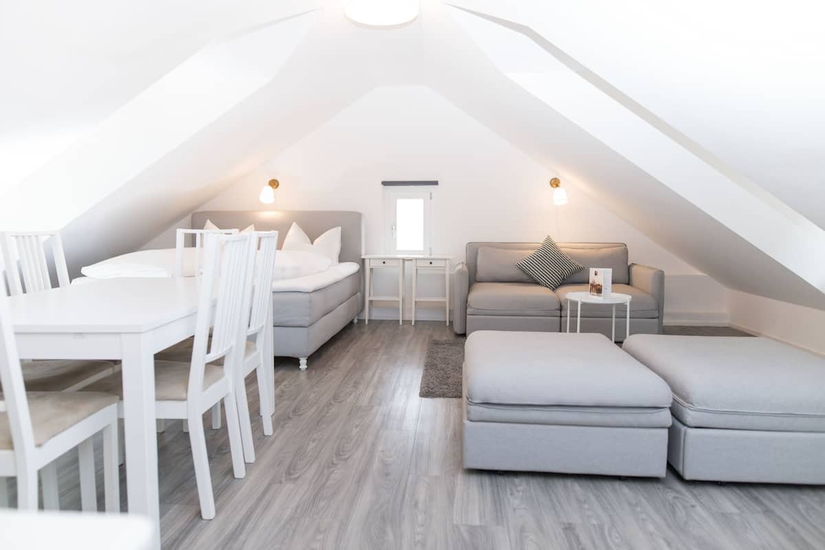 A modern loft bedroom with a dining area, a sofa, and a small table.
